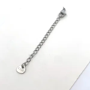 Close-up of a stainless steel jewelry extension chain with lobster clasp and S.Steel tag