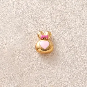 Gros plan d'une perle de lapin dorée avec nœud rose et cœur pour créations de bijoux DIY.