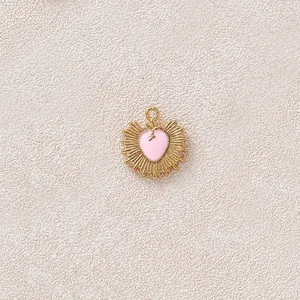 Dettaglio del cuore in smalto rosa e della placcatura in oro a raggiera sul ciondolo.