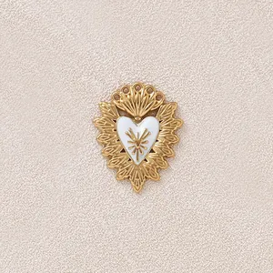 Dettaglio di un ciondolo a cuore vintage placcato in oro con corona e smalto bianco