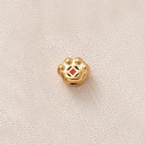 Détail d'une breloque en forme de patte dorée avec émail rouge pour création de bijoux
