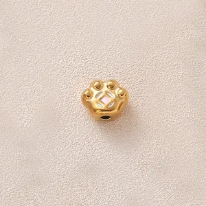 Vue macro détaillée d'une perle en forme de patte dorée avec émail rose pour bijoux DIY créatifs