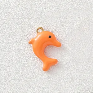 Close-up of bright orange dolphin enamel charm with gold-plated loop for DIY jewelry