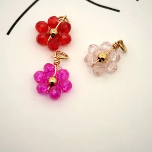 Macro view of crystal flower charms in red, pink, and purple with gold plating