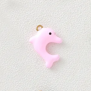 Macro detail of a pink oil-dripping dolphin pendant with a gold-plated jump ring accessory