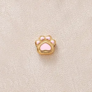 Gros plan d'une perle patte de chat en émail rose et acier inoxydable doré pour bijoux DIY.