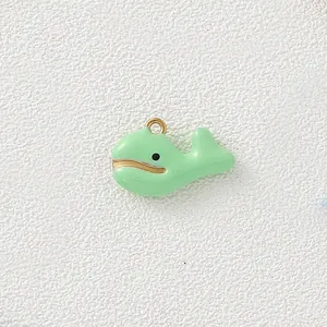 Macro view of a light green enamel whale charm with elegant gold-colored metal edges