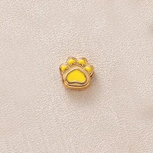 Vue détaillée d'une perle breloque patte dorée avec un remplissage en émail jaune.