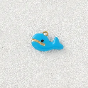 Detailed macro view of a cute blue enamel whale charm with gold-plated stainless steel edges