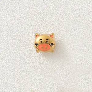 Close-up view of a gold-plated pig bead with pink enamel for DIY jewelry making