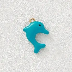 Close-up of teal blue enamel dolphin pendant with gold ring for DIY necklace and bracelet