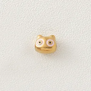 Detailed view of a golden stainless steel cartoon cat bead with pink enamel eyes