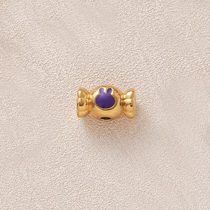 Gros plan d'une perle bonbon dorée avec un lapin en émail violet pour bijoux DIY.