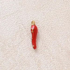 Nahaufnahme eines roten Emaille-Chili-Anhängers mit vergoldeten Metalldetails.