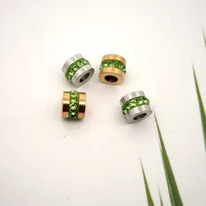 Macro detail of stainless steel spacer beads with inlaid green zircon crystals for jewelry