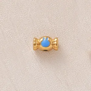 Vue macro d'une perle dorée en forme de bonbon avec un motif de lapin en émail bleu