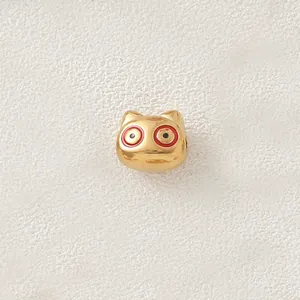 Close-up of gold-plated pig charm bead with red and black enamel eyes for DIY jewelry