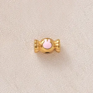 Gros plan sur perle bonbon dorée avec motif lapin en émail rose pour bijoux DIY