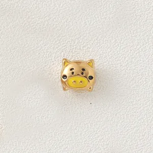 Detailed view of a gold-plated stainless steel pig bead with yellow enamel details