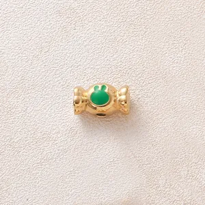 Vue détaillée d'une perle bonbon dorée avec un motif de patte de lapin en émail vert
