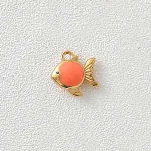 Close-up of a gold-plated stainless steel fish pendant with coral enamel detail