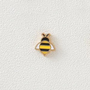 Detailed view of a small 18K gold-plated bee charm with colorful enamel dripping oil.