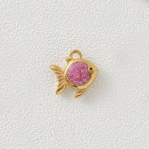 Close-up of a gold-plated stainless steel fish pendant with pink glitter inlay.