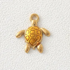 Macro detail of a gold-plated stainless steel sea turtle charm with yellow enamel shell.