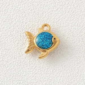 Macro view of a gold-plated fish pendant with blue glitter detail for DIY jewelry.