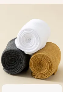 Nahaufnahme von drei aufgerollten Baumwoll-Wadensocken in Weiß, Dunkelgrau und Senfgelb
