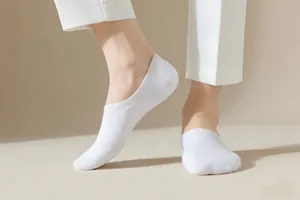 Side view of men's white low-cut invisible boat socks worn with trousers