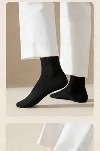 Close-up detail of men's breathable black cotton crew socks worn with white trousers