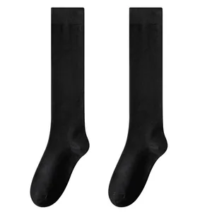 Ein Paar klassische schwarze kniehohe Baumwollsocken für Damen im minimalistischen JK-Stil.