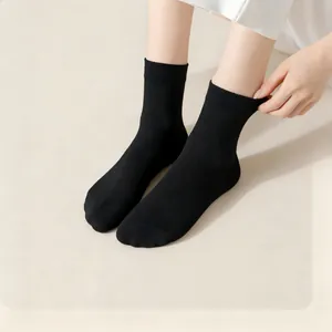 Detailed close-up view of breathable solid black crew socks worn by a model in a studio.