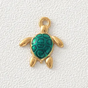 Macro view of a gold-plated stainless steel turtle charm with green enamel shell detail.
