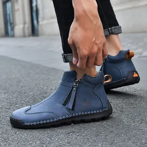 Close-up of blue hand-stitched men's boots with side zipper and orange pull tab