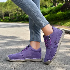 Detailed view of purple suede shoes with hand-stitched soles and side zipper