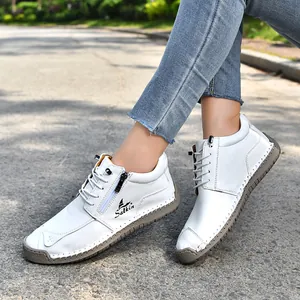 Detail shot of white handmade stitched casual shoes with side zipper and grey sole