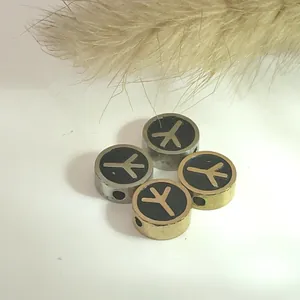 Close-up view of stainless steel round beads with black oil drop and symbol pattern