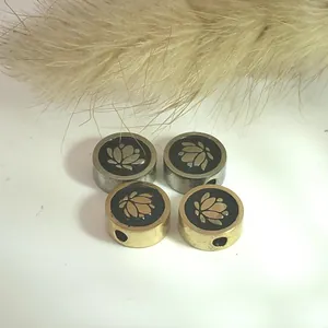 Detail of stainless steel lotus charms with black enamel finish for jewelry making.