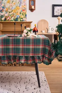 Detail of a green and red Christmas plaid tablecloth with ruffled edges in a cozy room