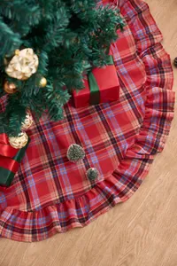 Red plaid Christmas tree skirt with festive ruffle trim detail under decorated tree
