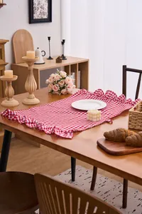 Decorative red and white checkered hand towel with ruffled edges shown on a wooden table