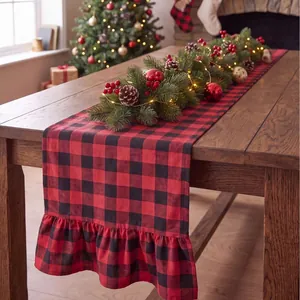 Red and black buffalo plaid Christmas table runner with ruffled edges on a wooden table.