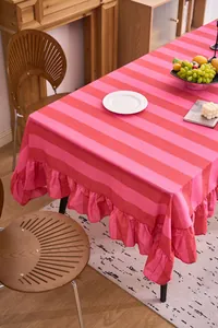 Mantel de algodón y lino a rayas rojas y rosas con detalle de volantes en una mesa.