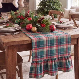 Close-up detail of a festive red and green plaid table runner with ruffled hem for Christmas.