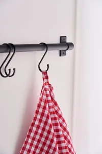 Detail of red and white plaid hand towel hanging on a black hook.