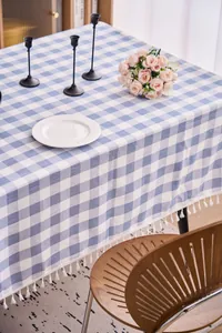 Detail shot of a blue and white checkered linen tablecloth with delicate white tassels