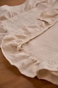 Gedetailleerde close-up van de elegante rufflerand en textuur van beige katoen linnen placemat