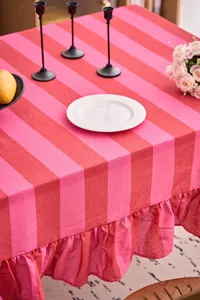 Detalle de mantel a rayas rosas y rojas con elegante borde de volantes y textura lino